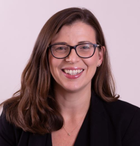 Woman with long brown hair and glasses smiling