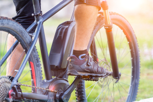 e-bike frame with black battery and a mans leg on the pedal